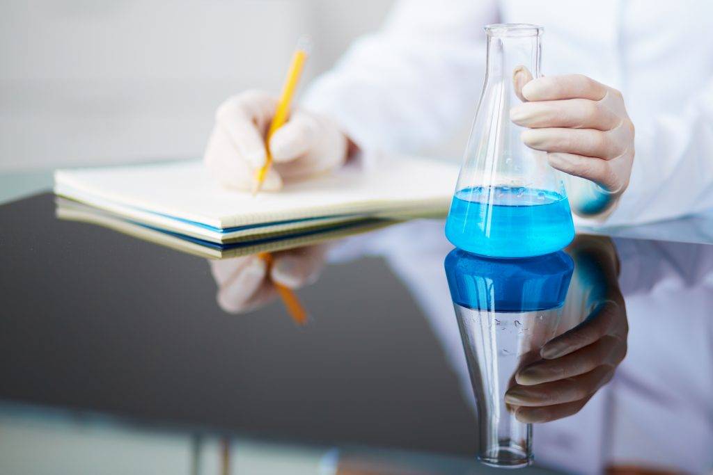 graphicstock-image-of-glass-flask-with-blue-liquid-held-by-female-chemist-in-laboratory_rxgh7P1Wxb-scaled